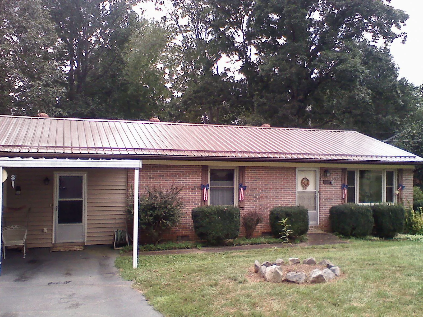 Bronze metal roof and carport on a brick ranch home — Roof Repair work by our crew in Picayune